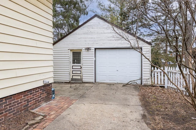 garage featuring concrete driveway and fence