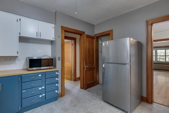 kitchen with radiator heating unit, light countertops, appliances with stainless steel finishes, white cabinetry, and blue cabinets