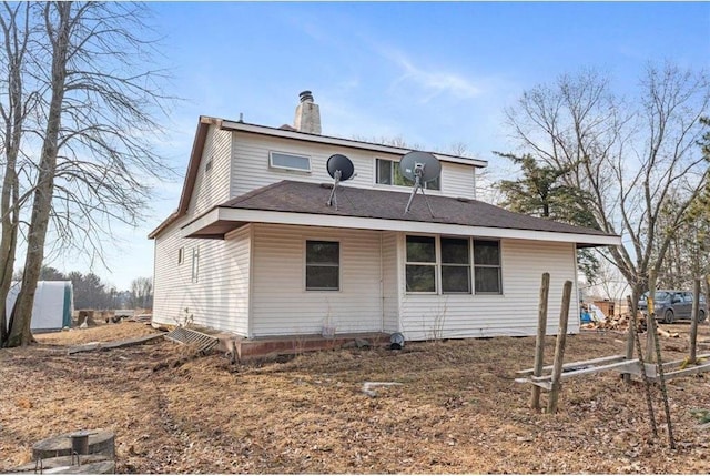 rear view of property featuring a chimney and a shingled roof