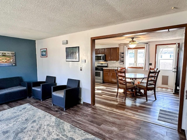 living room with dark wood-type flooring, ceiling fan, and a textured ceiling