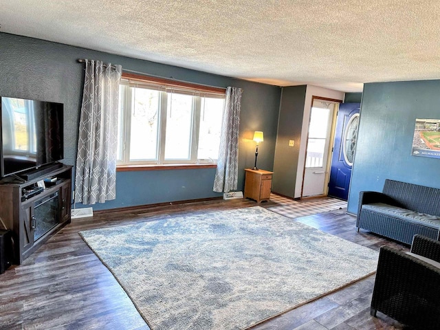 living area with a healthy amount of sunlight, a textured ceiling, and wood finished floors