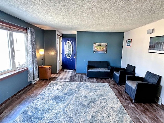 living room with a textured ceiling, baseboards, and wood finished floors