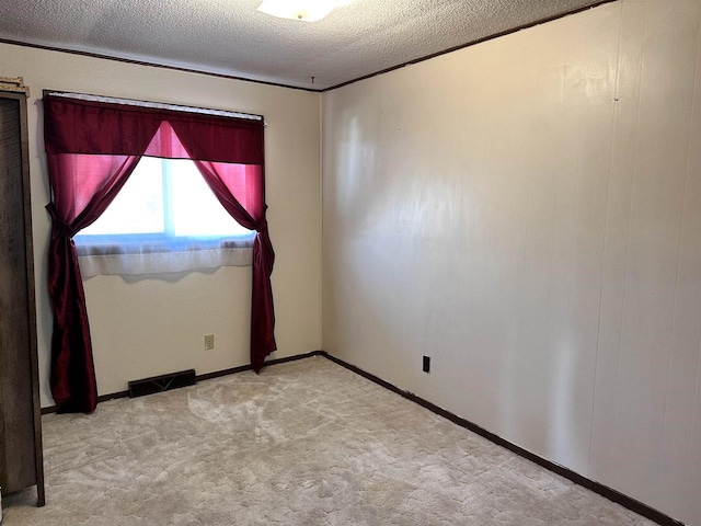 empty room featuring light carpet, visible vents, and a textured ceiling