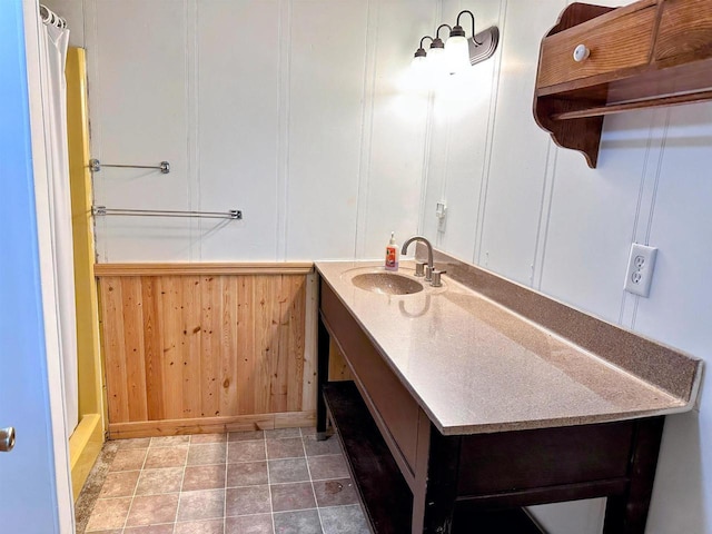 bathroom with curtained shower, tile patterned floors, a decorative wall, and vanity