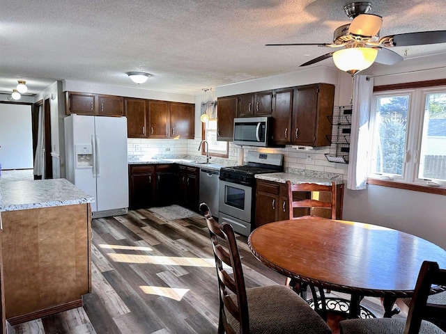 kitchen with a ceiling fan, dark wood-style floors, stainless steel appliances, light countertops, and dark brown cabinets