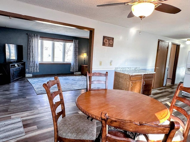 dining space featuring a textured ceiling, wood finished floors, and ceiling fan