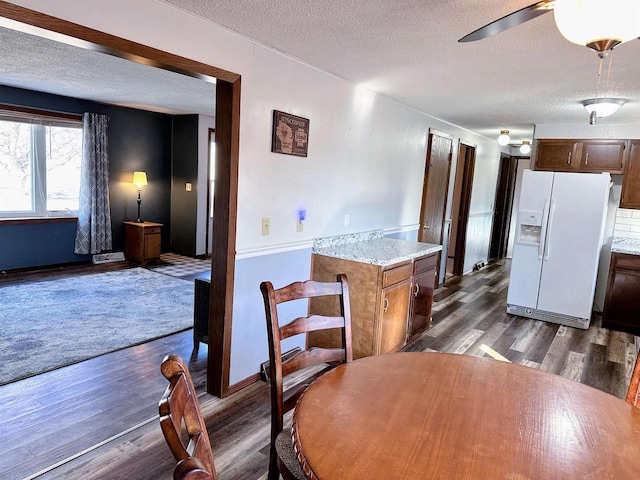 dining area featuring a textured ceiling, ceiling fan, and dark wood-style flooring