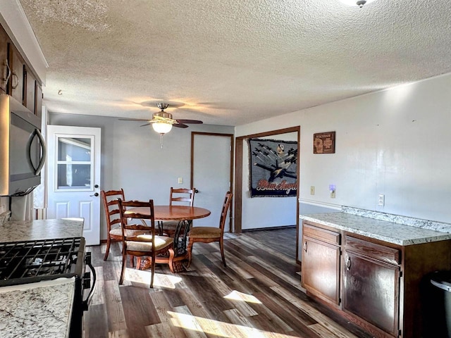 dining room featuring a textured ceiling, dark wood-type flooring, and ceiling fan