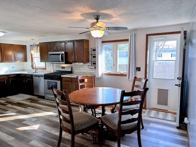 dining space featuring a textured ceiling, wood finished floors, and ceiling fan