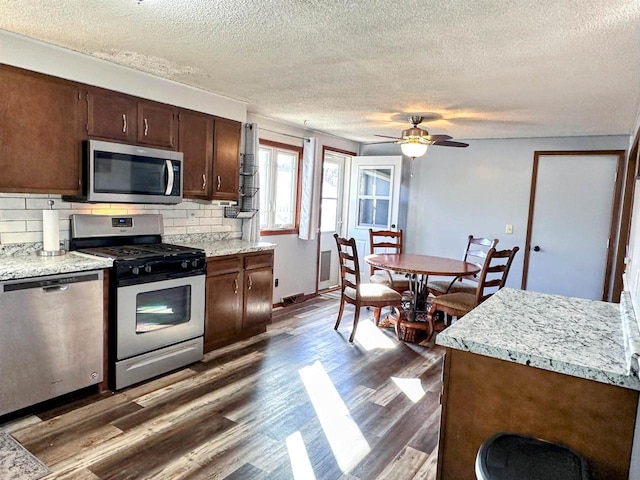 kitchen with tasteful backsplash, ceiling fan, dark brown cabinetry, appliances with stainless steel finishes, and dark wood-style floors