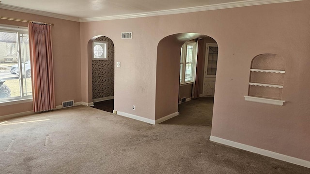 carpeted spare room featuring arched walkways, visible vents, and crown molding