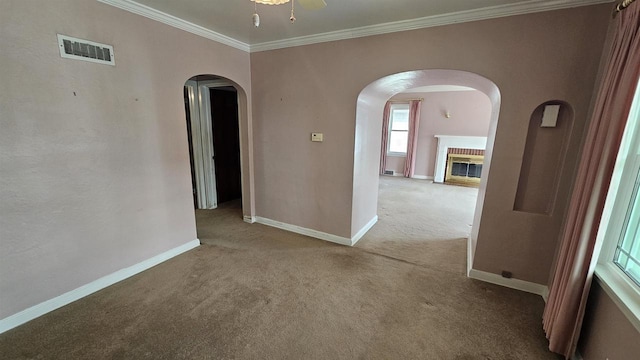 empty room with visible vents, baseboards, ornamental molding, carpet floors, and arched walkways