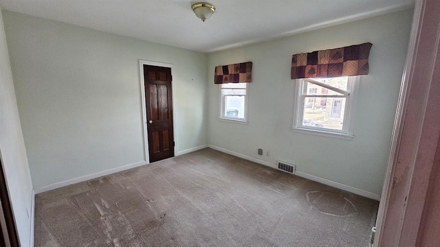 carpeted spare room featuring visible vents and baseboards