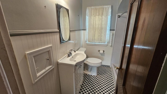 full bath with vanity, toilet, a stall shower, and wainscoting