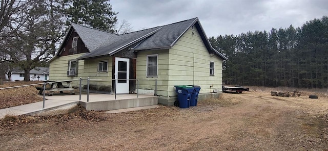 back of property with a patio and roof with shingles