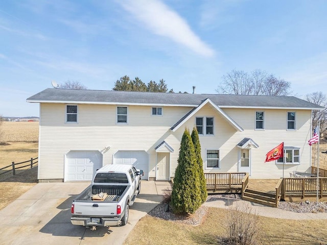 view of property featuring a garage, a deck, concrete driveway, and fence