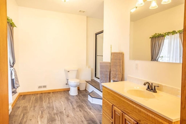 bathroom with toilet, wood finished floors, visible vents, and a stall shower