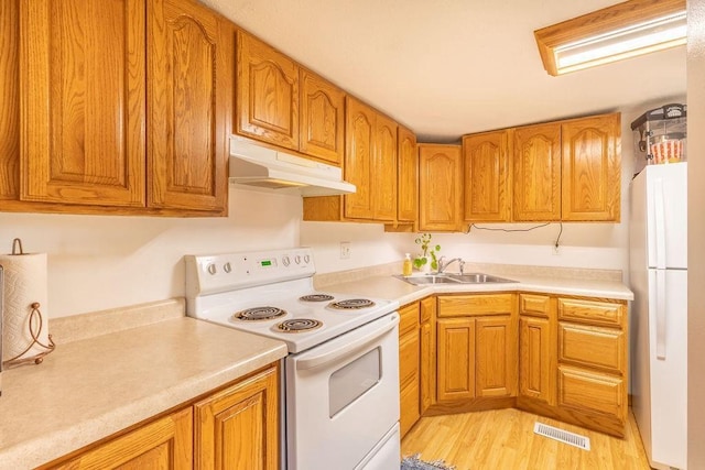 kitchen with visible vents, under cabinet range hood, a sink, white appliances, and light countertops