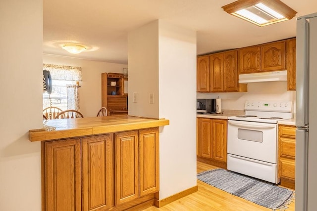 kitchen with white range with electric cooktop, under cabinet range hood, light wood-style floors, brown cabinetry, and light countertops