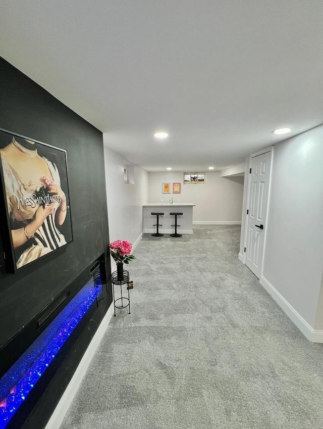 interior space with a glass covered fireplace, carpet flooring, and baseboards