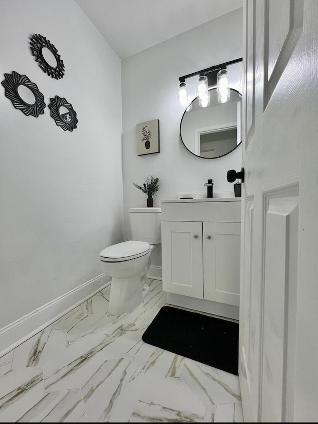 bathroom with marble finish floor, toilet, vanity, and baseboards