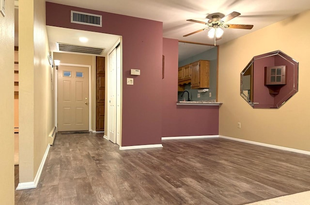 corridor featuring visible vents, a baseboard heating unit, baseboards, and dark wood-style flooring