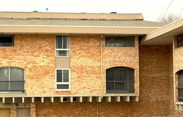 view of home's exterior with brick siding and a shingled roof