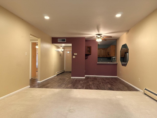 unfurnished living room featuring visible vents, a ceiling fan, a baseboard heating unit, dark carpet, and baseboard heating