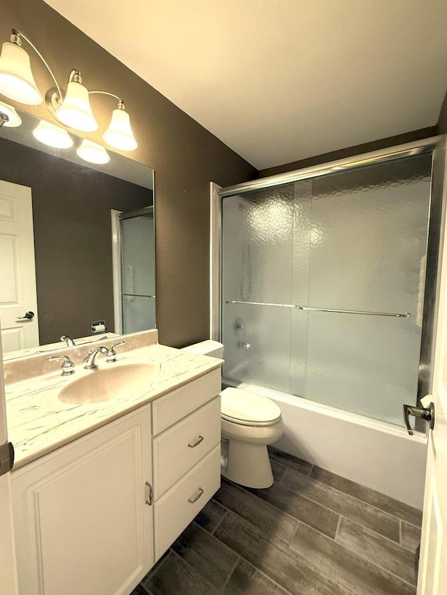 full bathroom featuring vanity, wood finish floors, toilet, and enclosed tub / shower combo