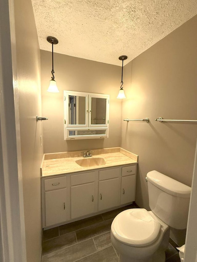 half bath featuring vanity, toilet, and a textured ceiling