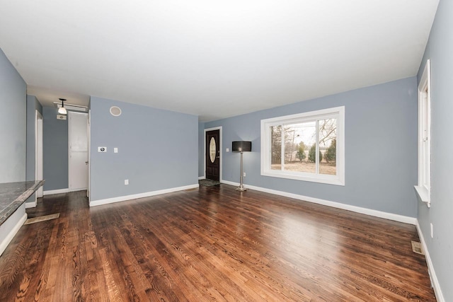unfurnished living room with baseboards and dark wood-style flooring