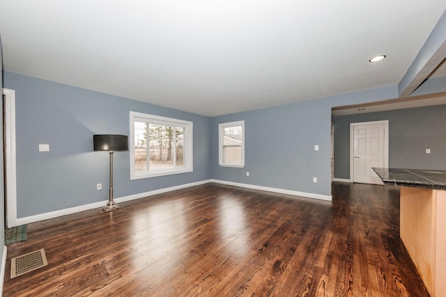unfurnished living room featuring visible vents, baseboards, and dark wood-style flooring