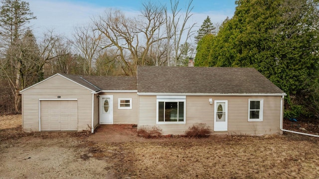 ranch-style home with an attached garage, a chimney, and a shingled roof