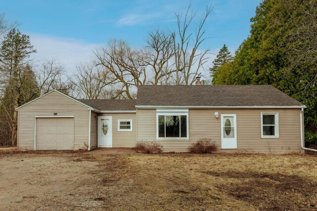 ranch-style home featuring a chimney, a garage, and dirt driveway