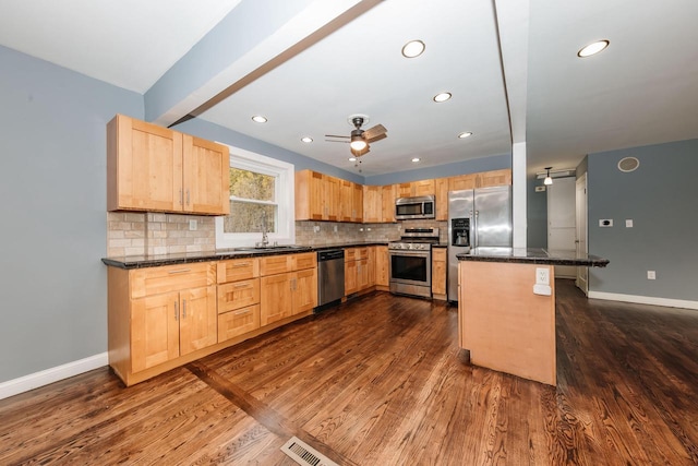 kitchen with light brown cabinets, tasteful backsplash, appliances with stainless steel finishes, and a sink