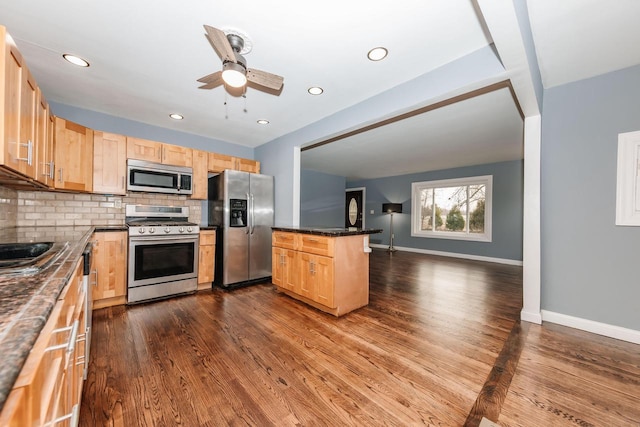 kitchen featuring dark countertops, decorative backsplash, light brown cabinets, and stainless steel appliances