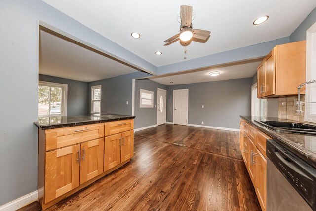 kitchen with tasteful backsplash, dark wood-type flooring, baseboards, stainless steel dishwasher, and a sink