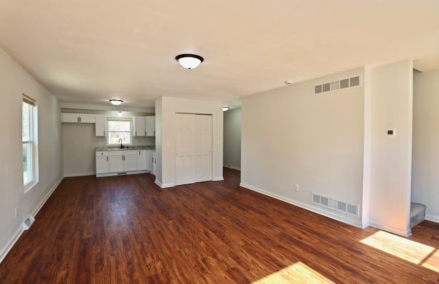 unfurnished living room with dark wood finished floors, visible vents, and a sink