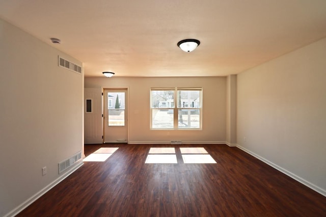 spare room with visible vents, baseboards, and dark wood-style floors