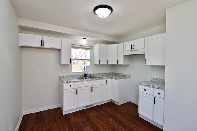 kitchen with under cabinet range hood, white cabinets, dark wood finished floors, and a sink