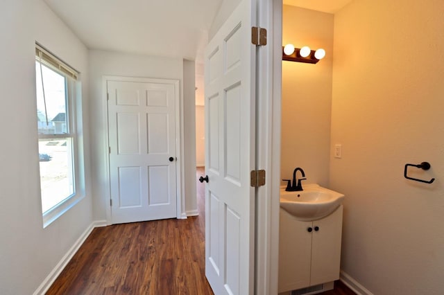 bathroom with a wealth of natural light, vanity, baseboards, and wood finished floors