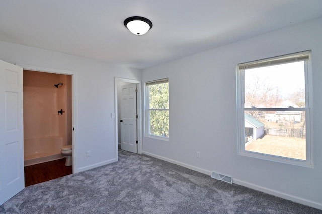 unfurnished bedroom featuring carpet flooring, baseboards, visible vents, and ensuite bathroom