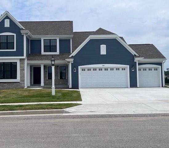 view of front of property featuring concrete driveway, an attached garage, and a front lawn