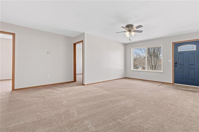 interior space featuring light colored carpet, baseboards, a textured ceiling, and a ceiling fan