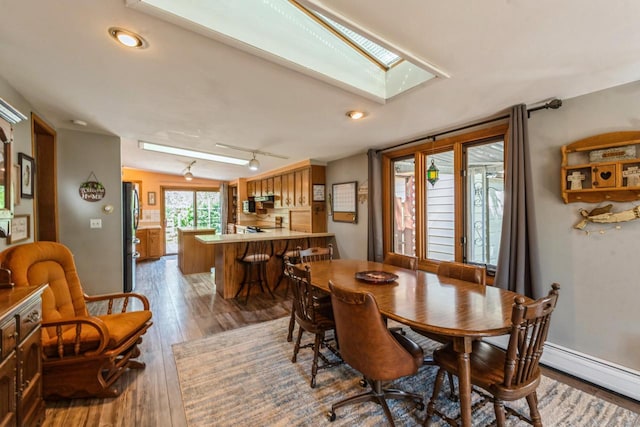 dining room with hardwood / wood-style floors, baseboards, a skylight, recessed lighting, and baseboard heating