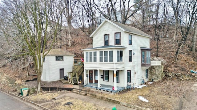 view of front of house with stairs, an outbuilding, and a sunroom