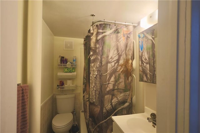 bathroom featuring vanity, a shower with shower curtain, toilet, and a wainscoted wall