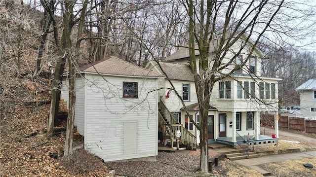 view of front facade with roof with shingles and fence