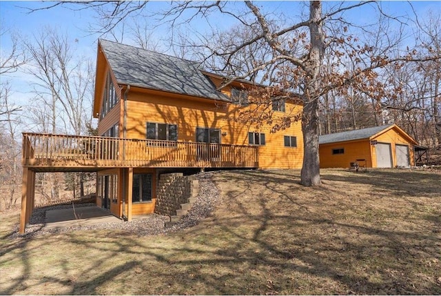 rear view of property featuring an outbuilding, a lawn, and a deck