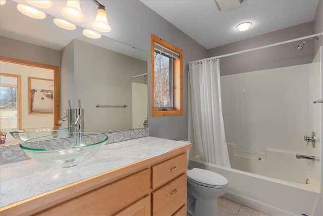 full bathroom featuring vanity, shower / bath combo, a textured ceiling, tile patterned floors, and toilet